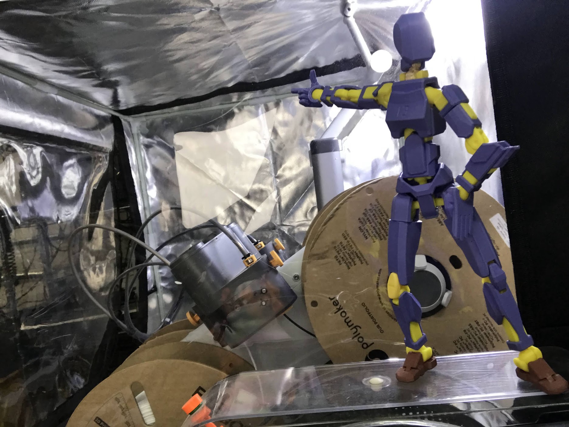 A purple and yellow 3D-printed Dummy Doll posed inside a workshop set