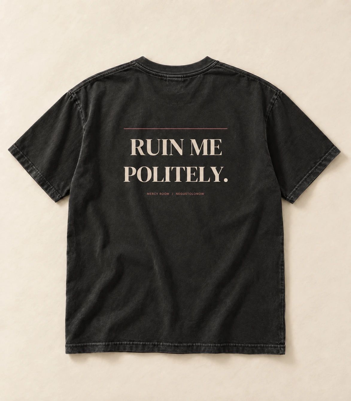 Washed black tee, laid flat, back up, with the line printed high across the shoulders in ivory